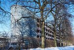 Mehrfamilienhaus mit Holzfassade hinter Bäumen